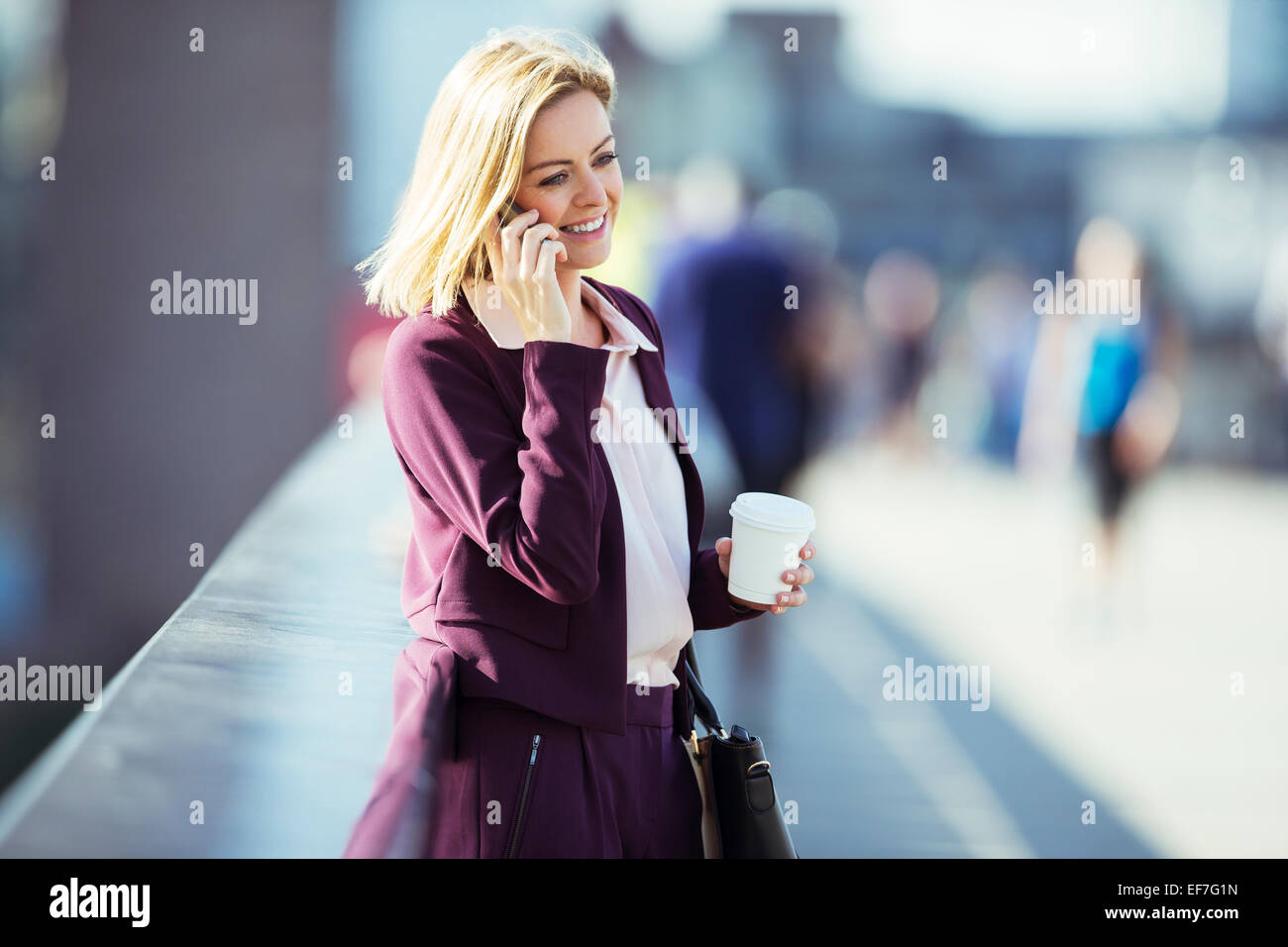 Businesswoman talking on cell phone on urban bridge Stock Photo