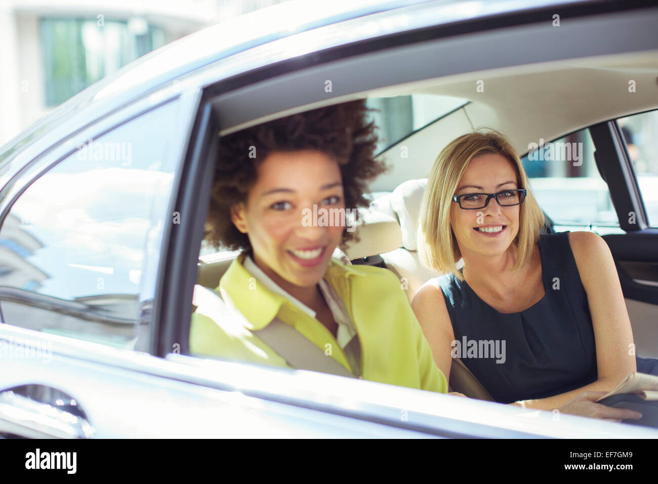 Businesswomen smiling in back seat of car Stock Photo