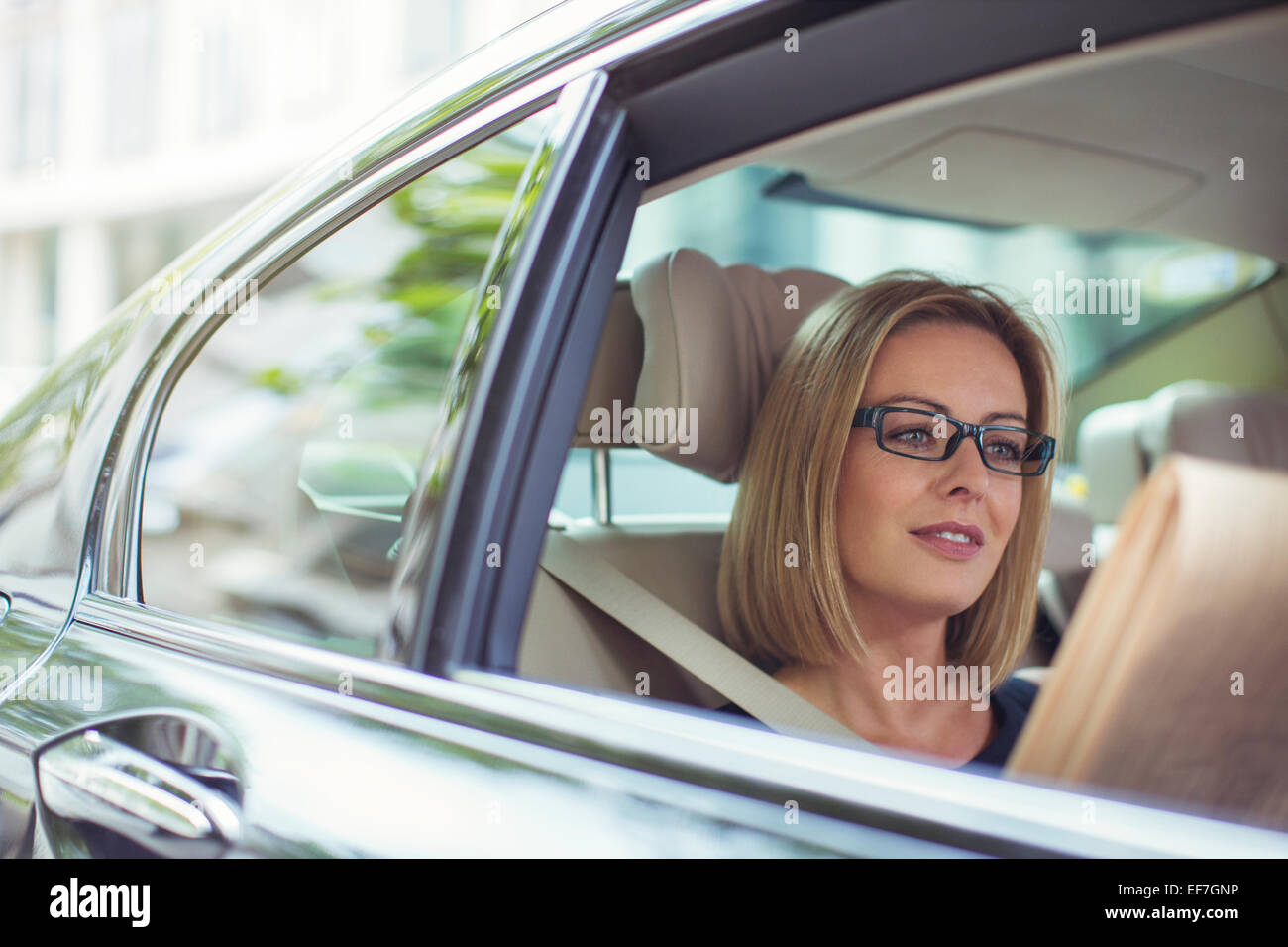 Businesswoman reading newspaper in back seat of car Stock Photo