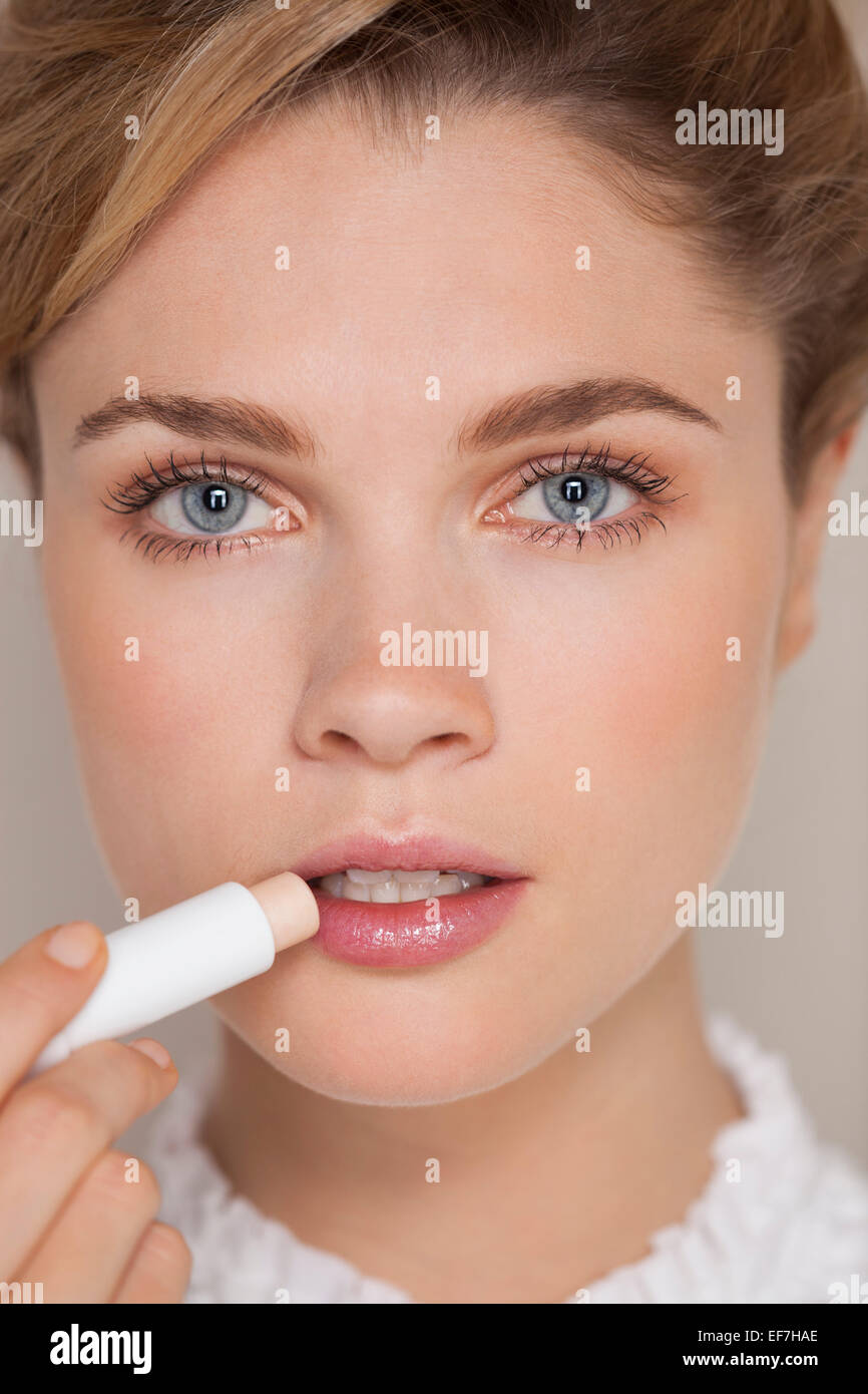 Beautiful woman applying lip balm Stock Photo