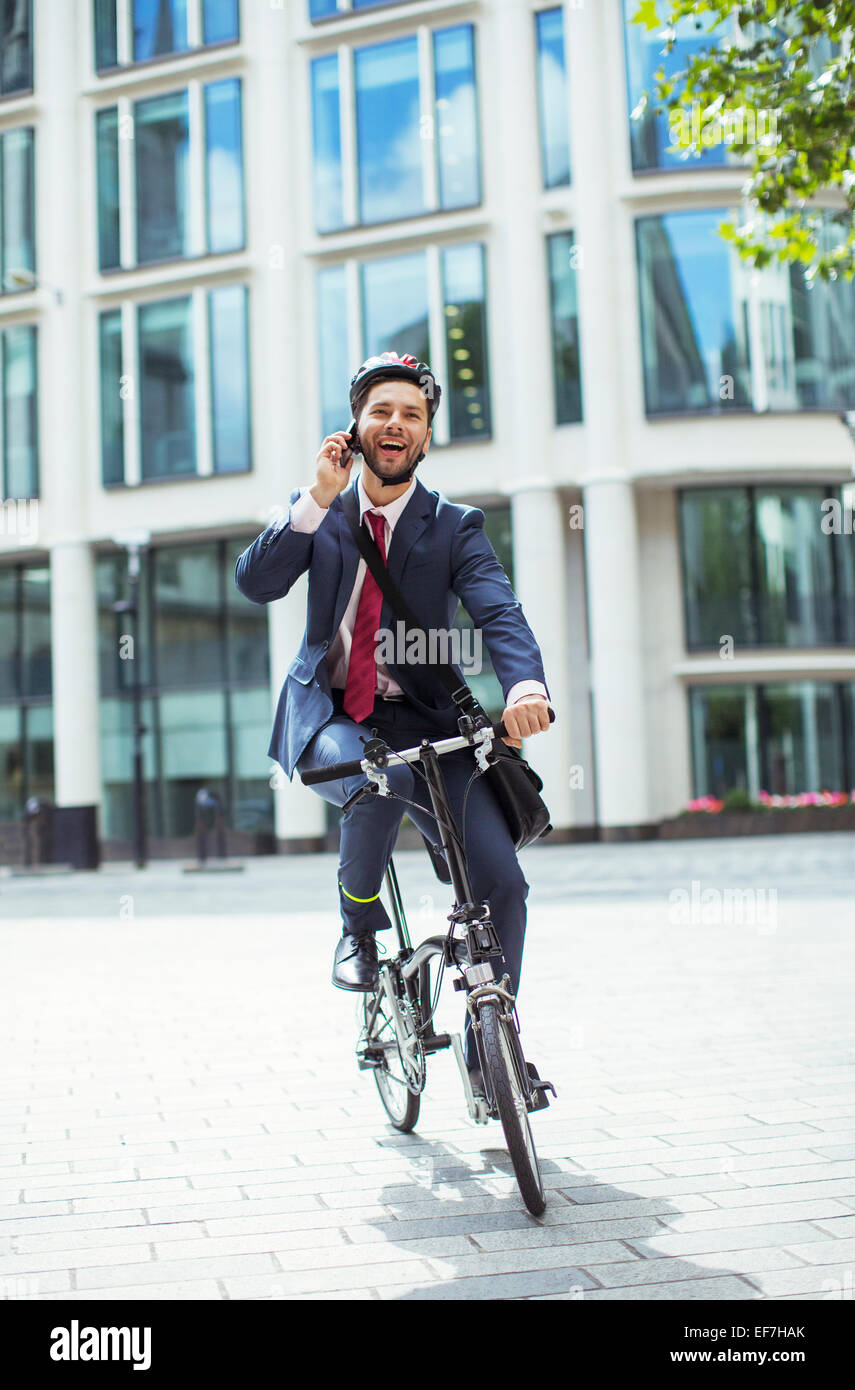 Businessman talking on cell phone on bicycle Stock Photo
