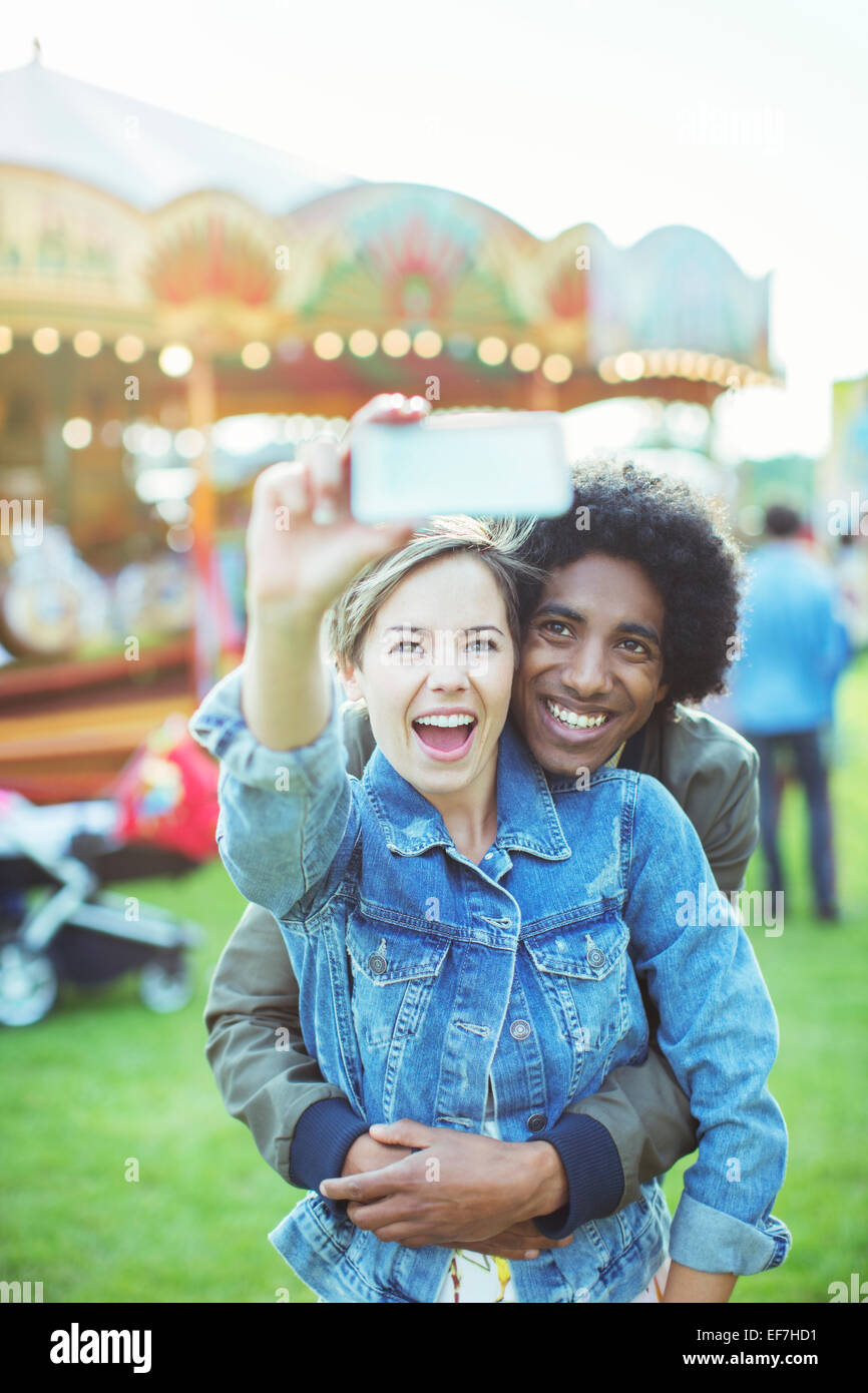 Young multiracial couple taking selfie in amusement park Stock Photo