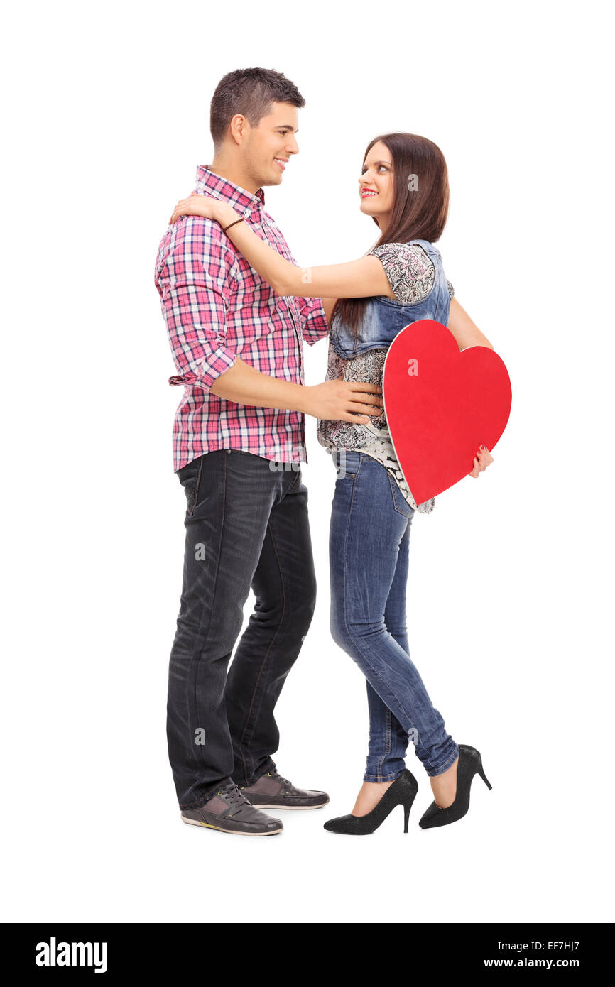Full length portrait of a girl holding a red heart and her boyfriend ...