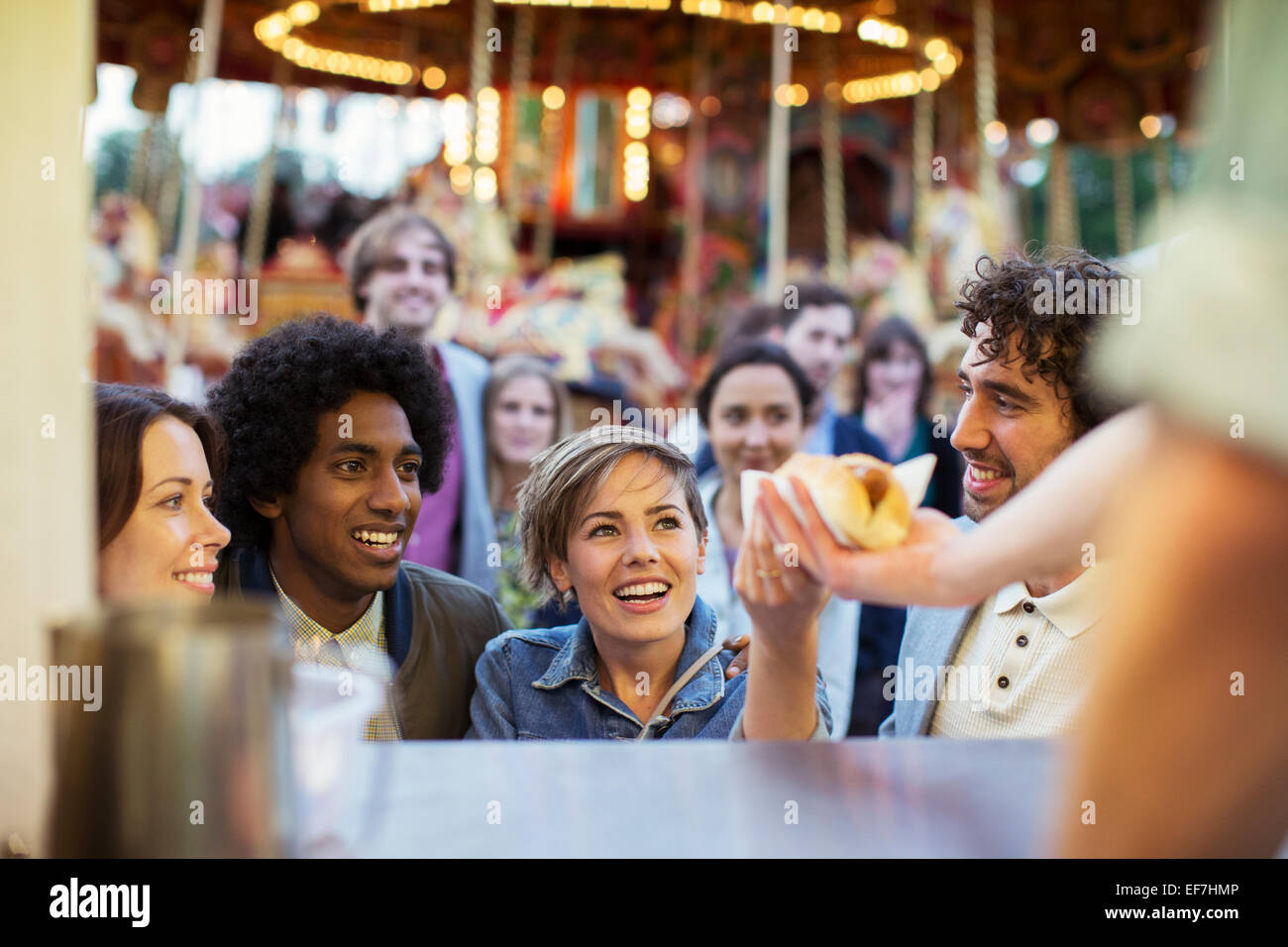 People buying hot dogs in food stand in amusement park Stock Photo