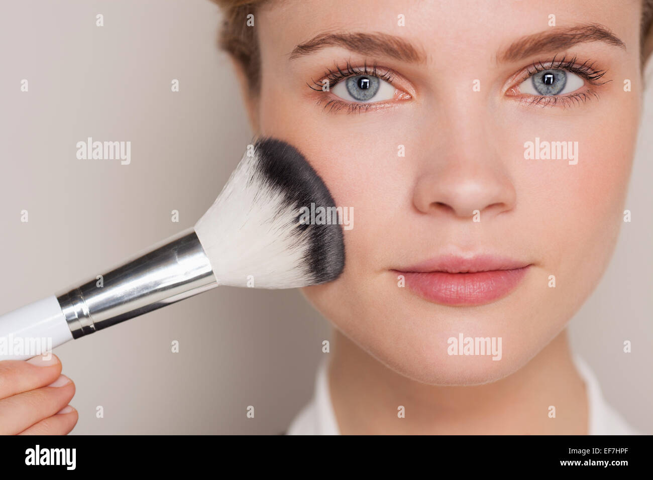 Beautiful woman applying make-up with a brush Stock Photo