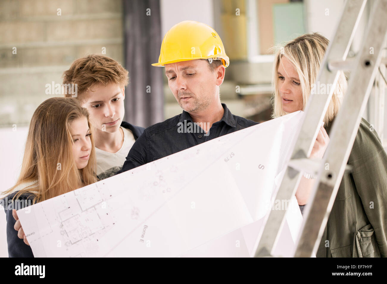 Engineer showing blueprint to family Stock Photo