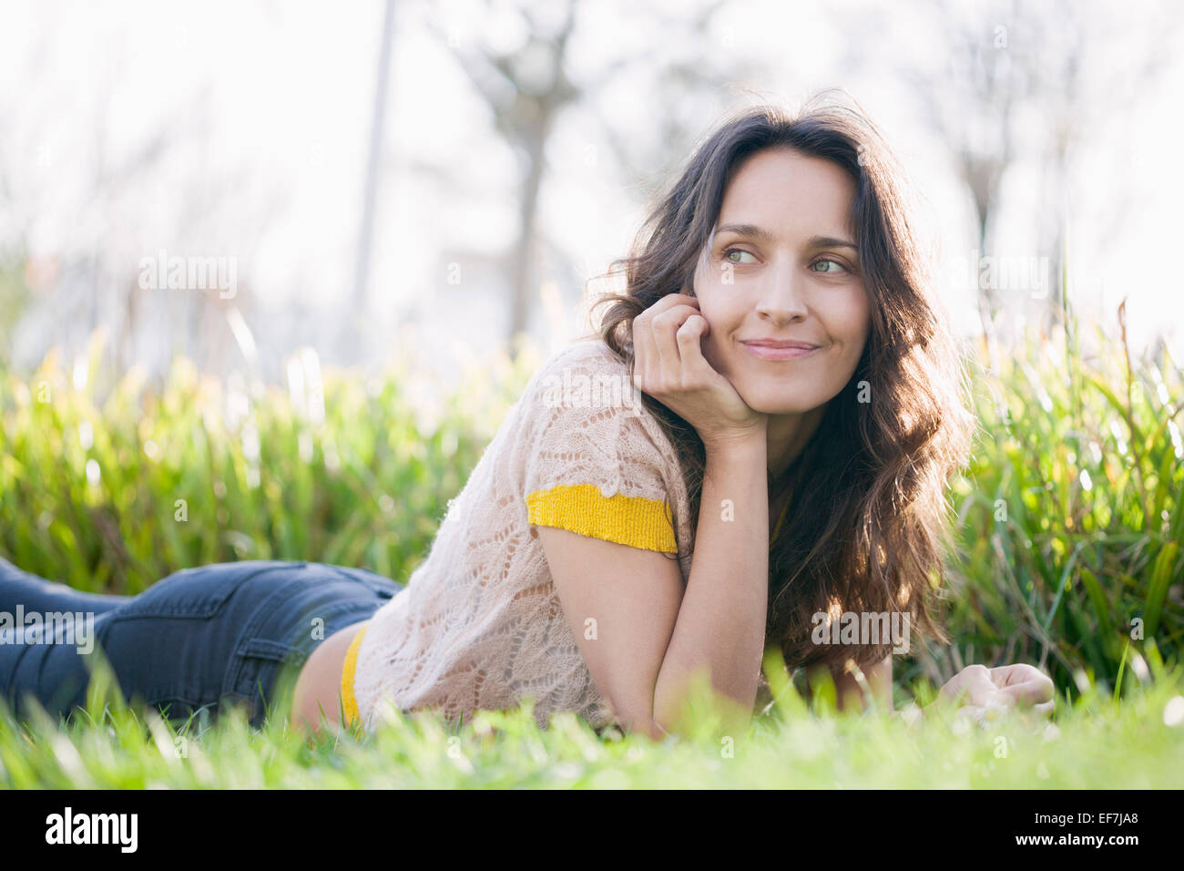 Happy beautiful woman lying on the grass Stock Photo