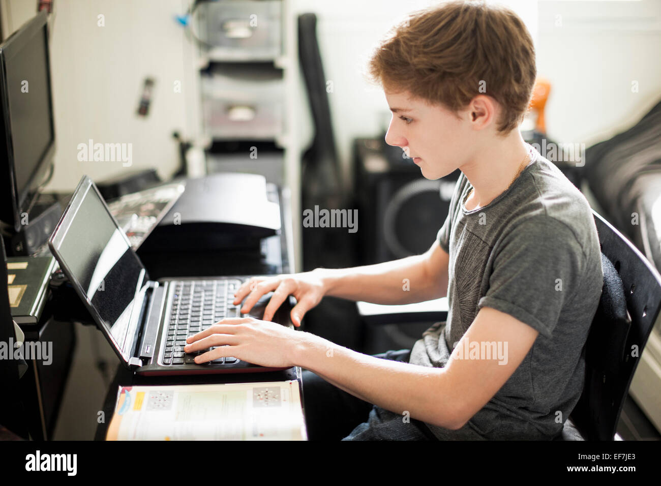 Teenage boy typing on laptop Stock Photo