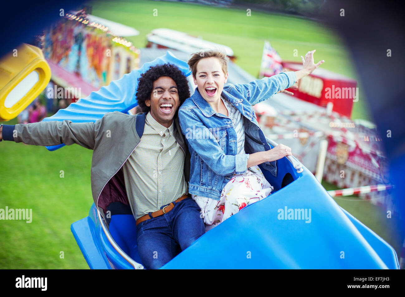 Cheerful couple having fun on carousel in amusement park Stock Photo