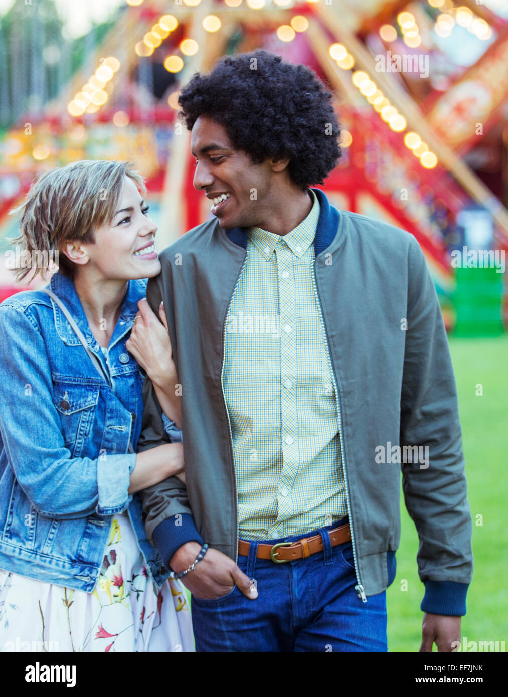 Young multiracial couple smiling to each other in amusement park Stock Photo