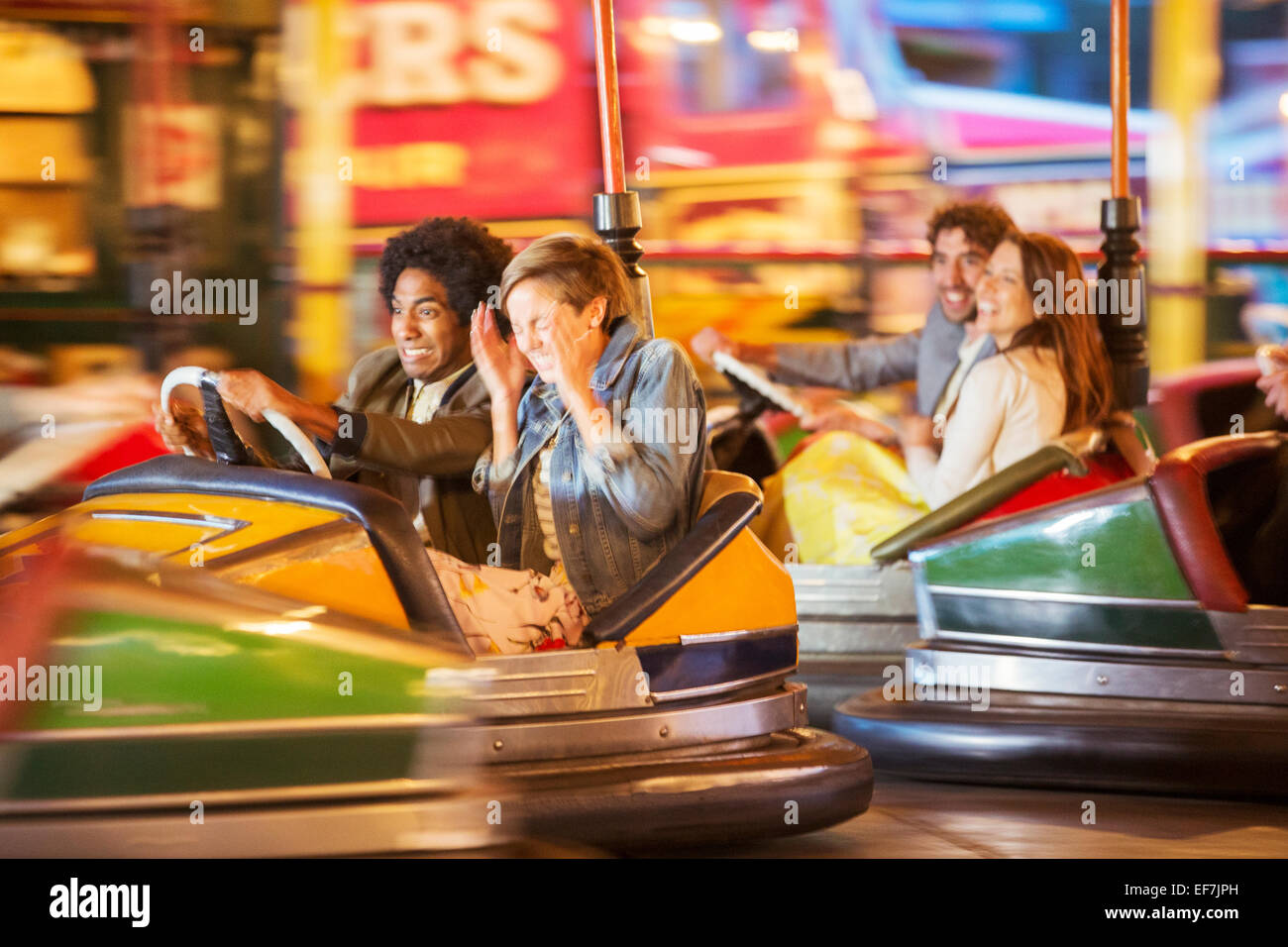 Group of friends having fun on bumper car ride in amusement park Stock Photo