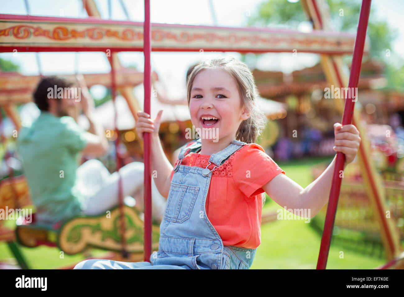 Cheerful girl laughing on carousel in amusement park Stock Photo