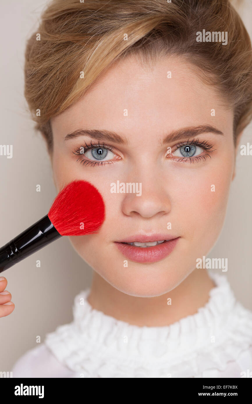 Portrait of a woman using makeup brush on her face Stock Photo Alamy