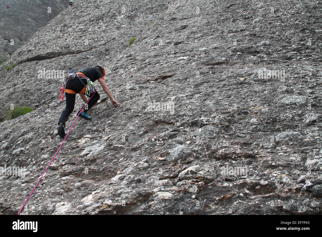 Rock climber climbing up side of mountain at Montserrat, Catalonia Stock Photo