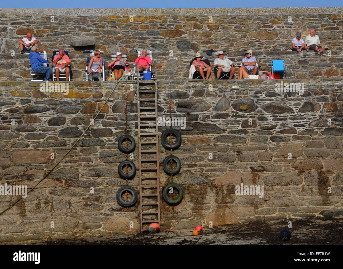 Enjoying the sunshine on the harbour wall at Mevagissey, Cornwall Stock Photo
