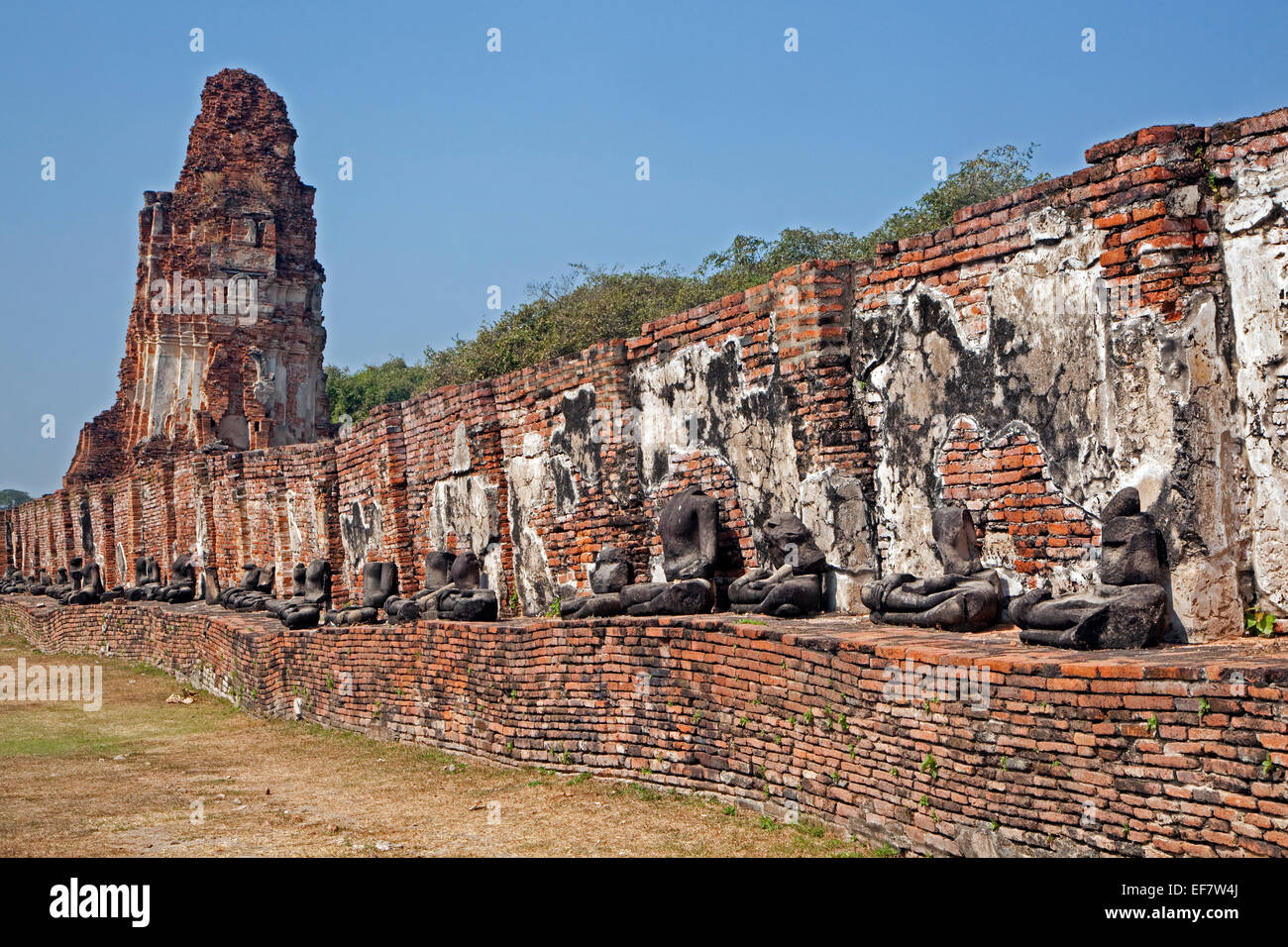 Ruin of Buddhist stupa with row of broken Buddha statues at Wat Mahathat in the Ayutthaya Historical Park, Thailand Stock Photo