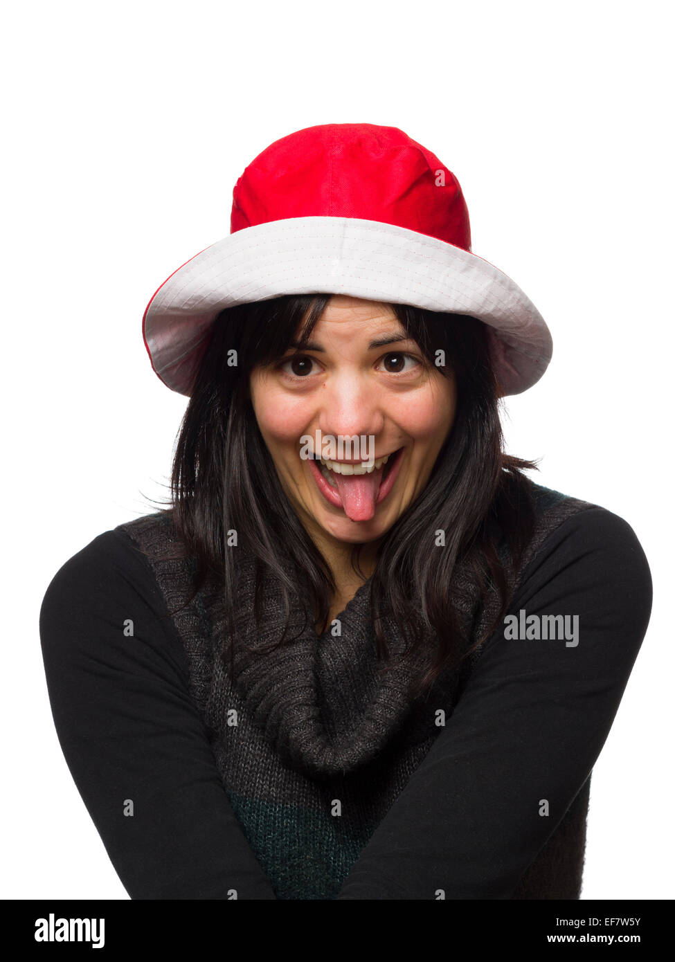 Goofy portrait of a woman doing goofy faces with her tongue out wearing a red hat isolated on white background Stock Photo