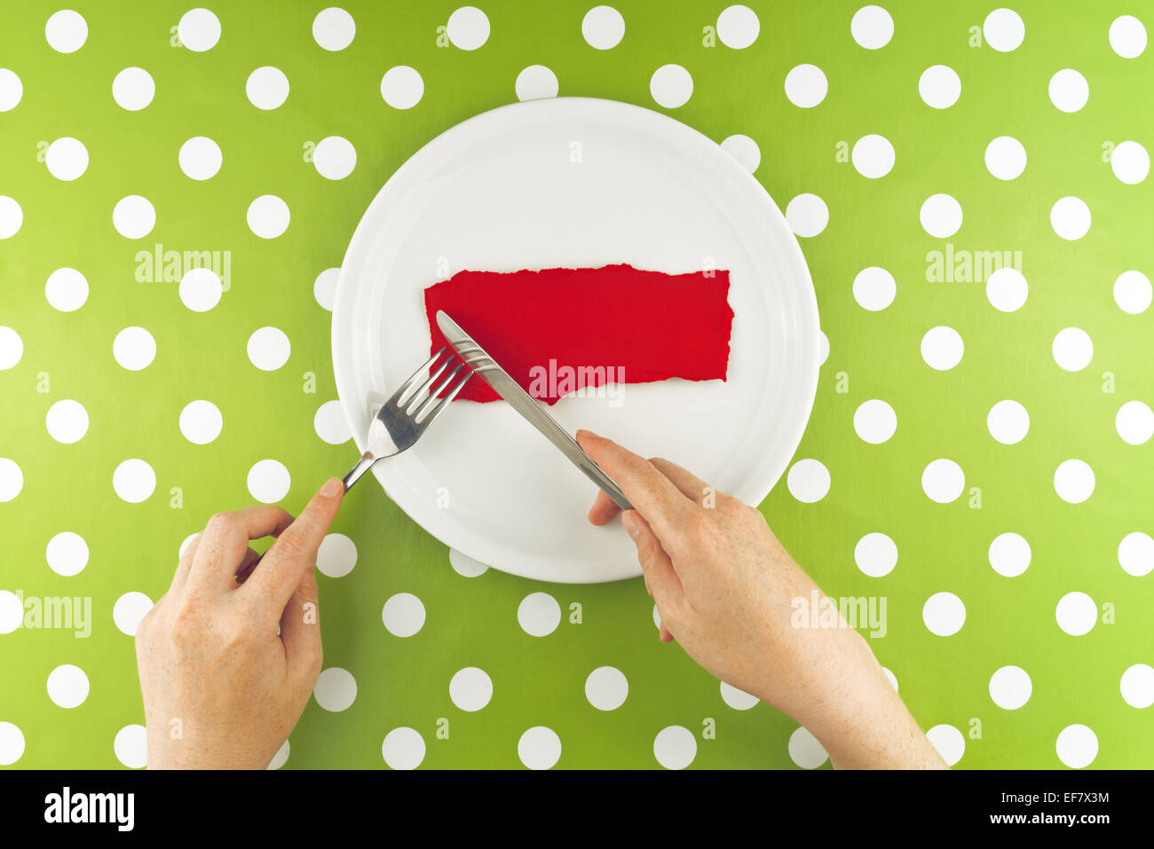 Woman eating from a white plate, top view with red paper as copy space. Stock Photo