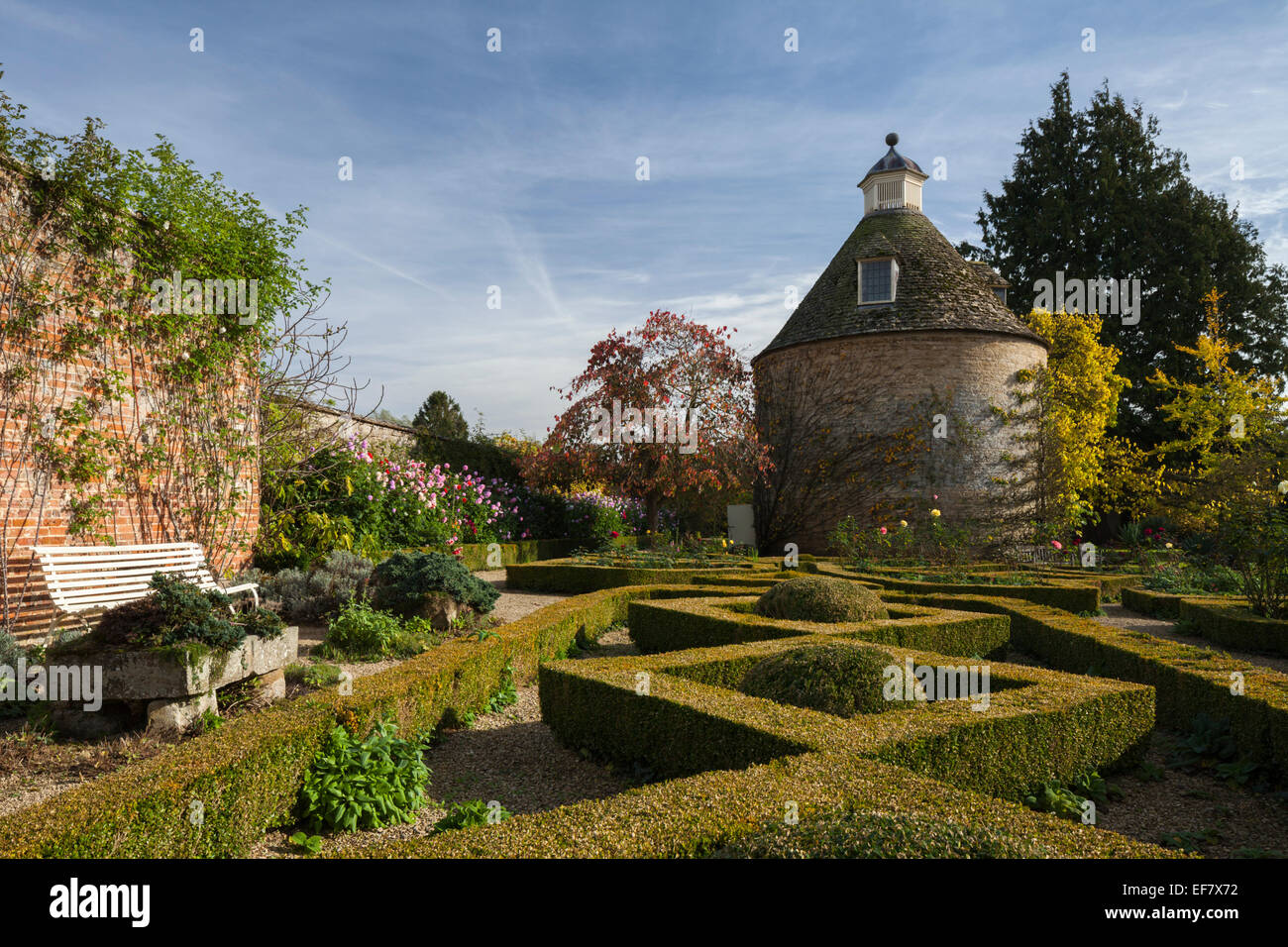 The geometric shapes of the box hedge parterre and c.1685 dovecote in the walled garden of Rousham House in early autumn, Oxfordshire, England Stock Photo