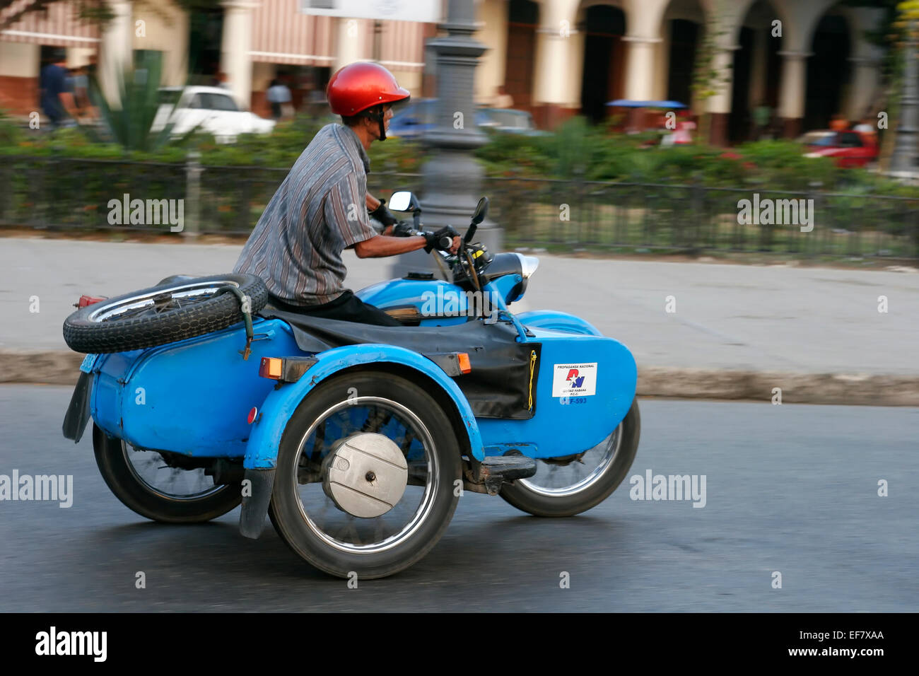 Cuban man riding vintage motorbike with sidecar, Havana, Cuba Stock Photo
