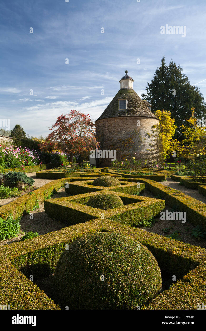 The geometric shapes of the box hedge parterre and c.1685 dovecote in the walled garden of Rousham House, Oxfordshire, England Stock Photo