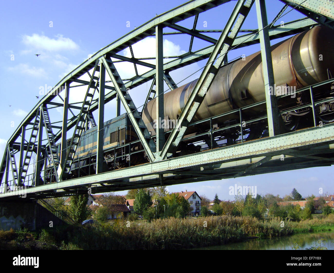 Transition locomotives and freight train over a metal bridge. Stock Photo