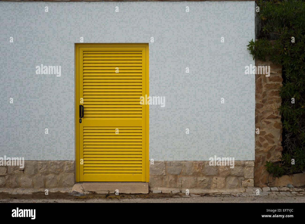 bright yellow door set in a white ceramic tiled wall in Luz Portugal Stock Photo