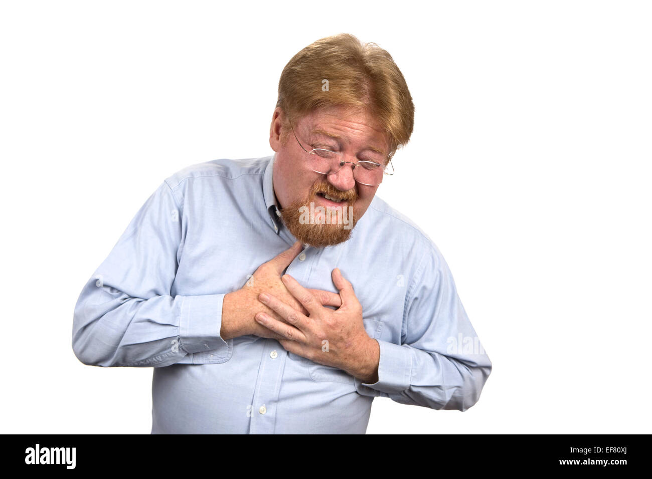 Mature man in his mid fifties clutches his chest as he reacts to heart attack pains. Stock Photo