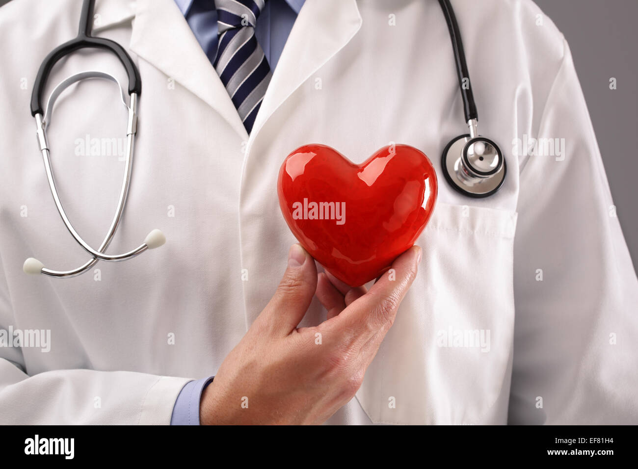 Doctor holding heart against chest Stock Photo