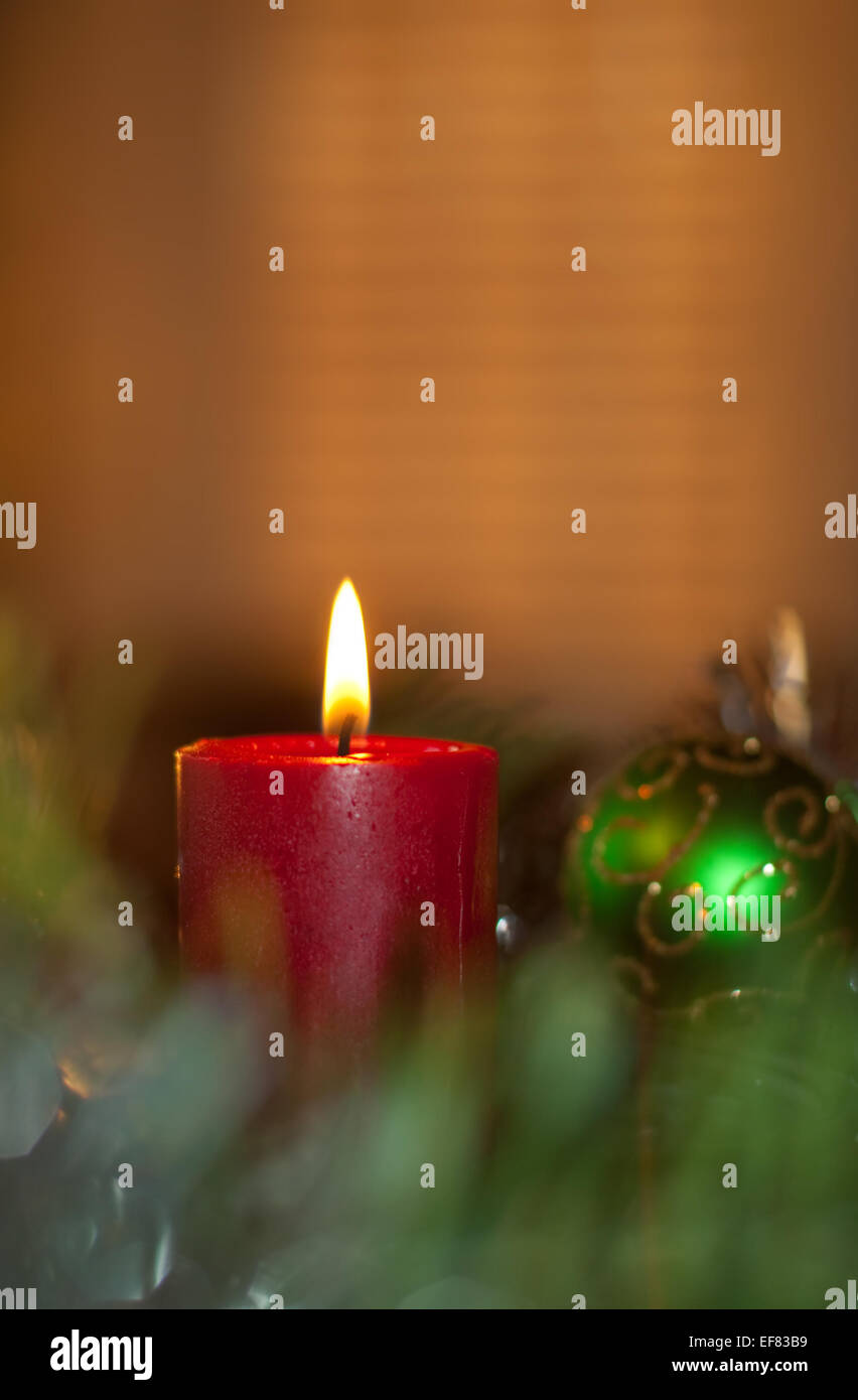 Red Christmas candle burning, surrounded by a wreath and decoration Stock Photo
