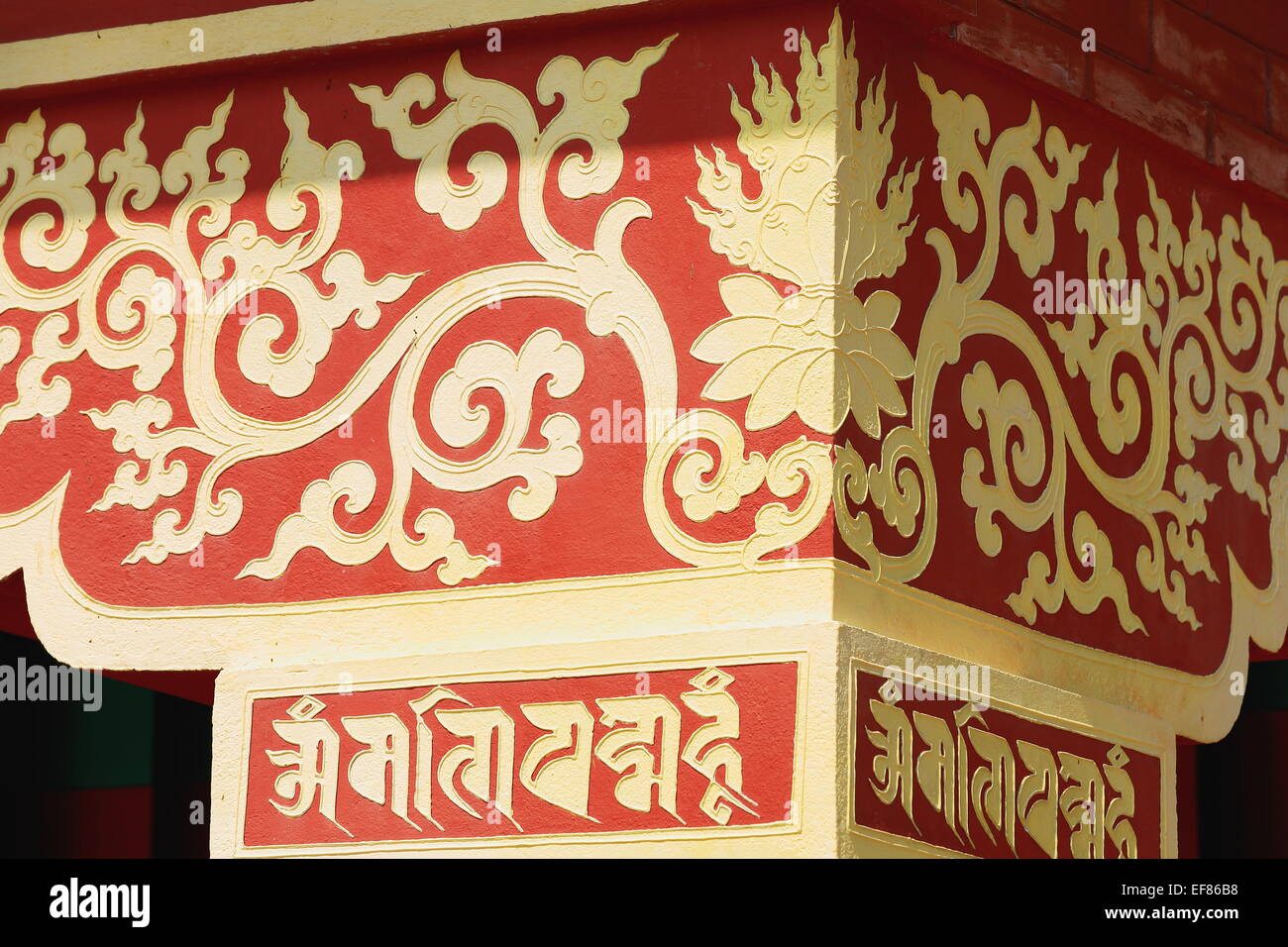Golden decoration on red painted chapiter of column showing traditional buddhist motifs-inner hall of Thrangu Tashi Yangtse m. Stock Photo