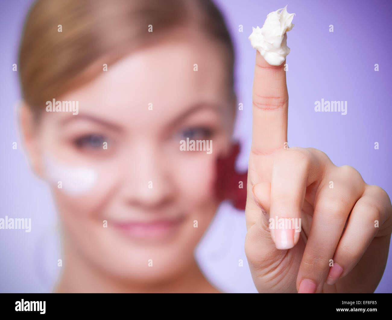 Skincare habits. Face of young woman with leaf as symbol of red capillary skin on gray. Girl taking care of her dry complexion a Stock Photo