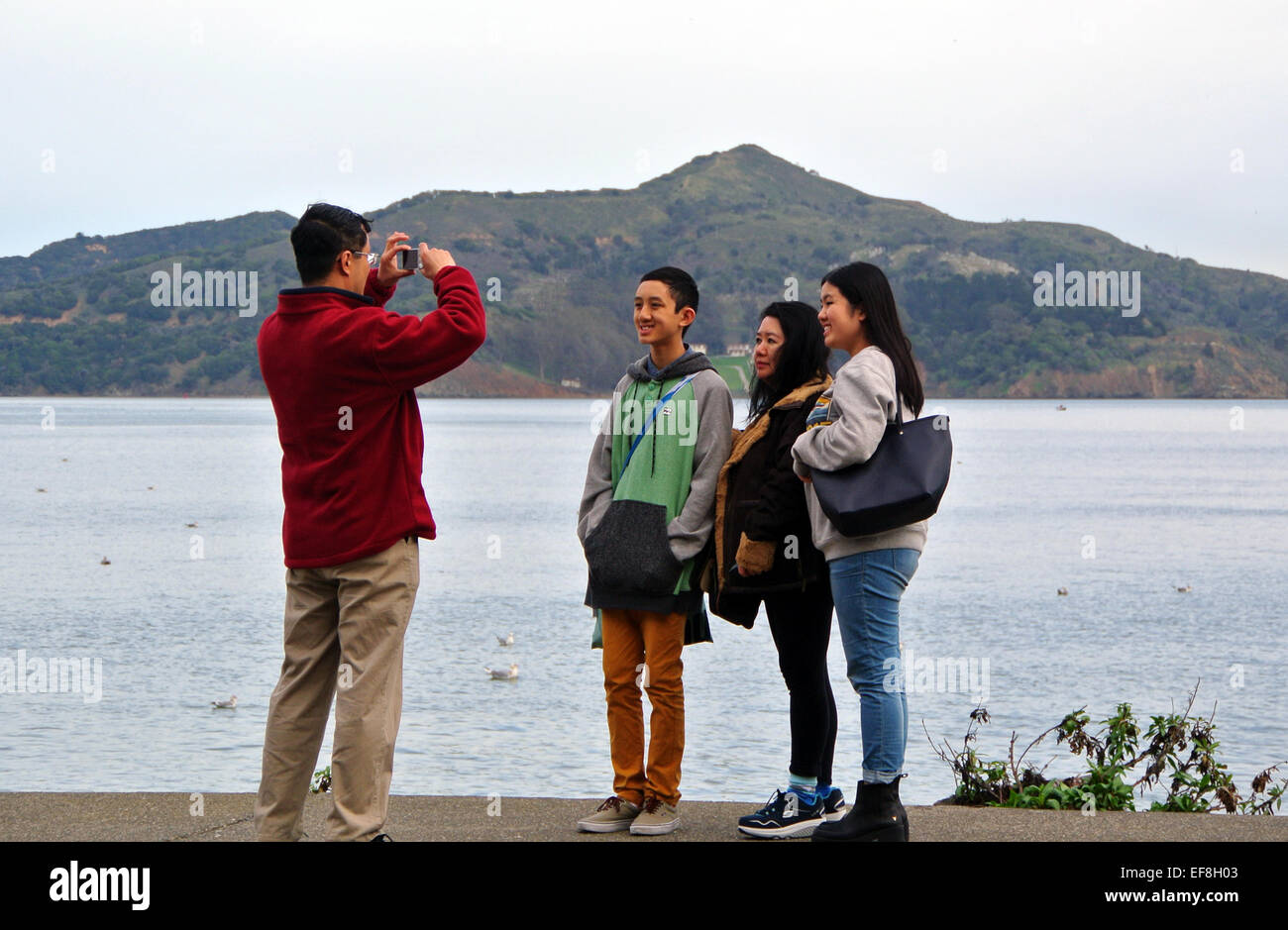 family poses for photograph in front of Angel Island from Sausalito sidewalk Stock Photo