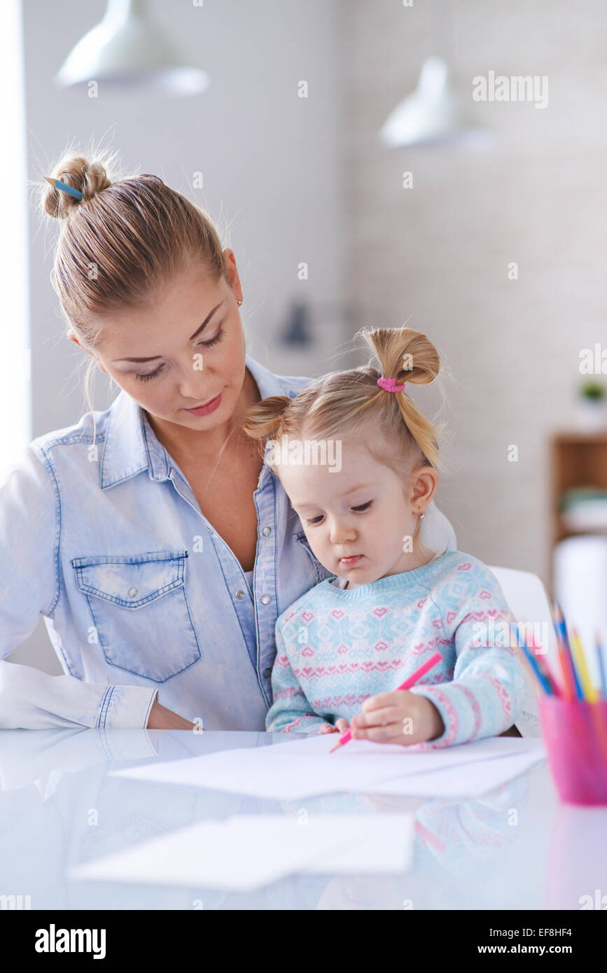 Little girl drawing with crayons with her mother near by Stock Photo ...
