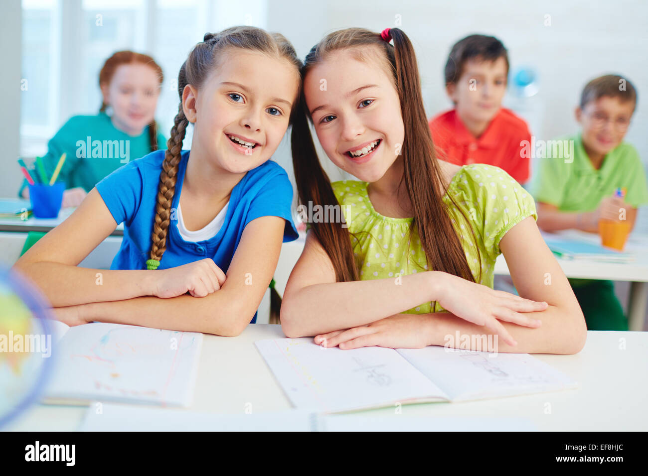 Cheerful schoolgirls looking at camera at lesson Stock Photo - Alamy