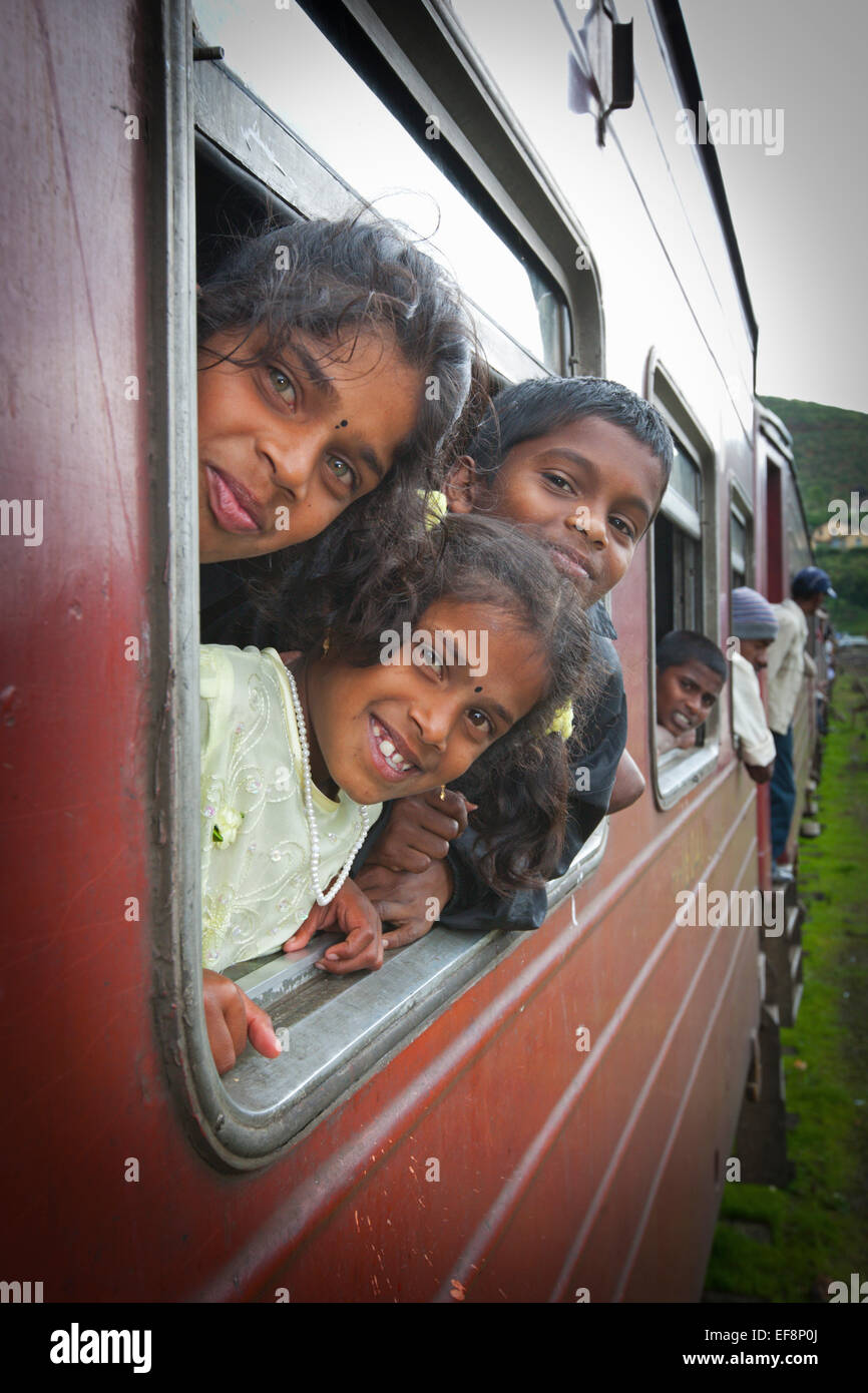 TAMIL CHILDREN LEANING OUT OF TRAIN WINDOW WHILE TRAVELLING NEAR HAPUTALE Stock Photo