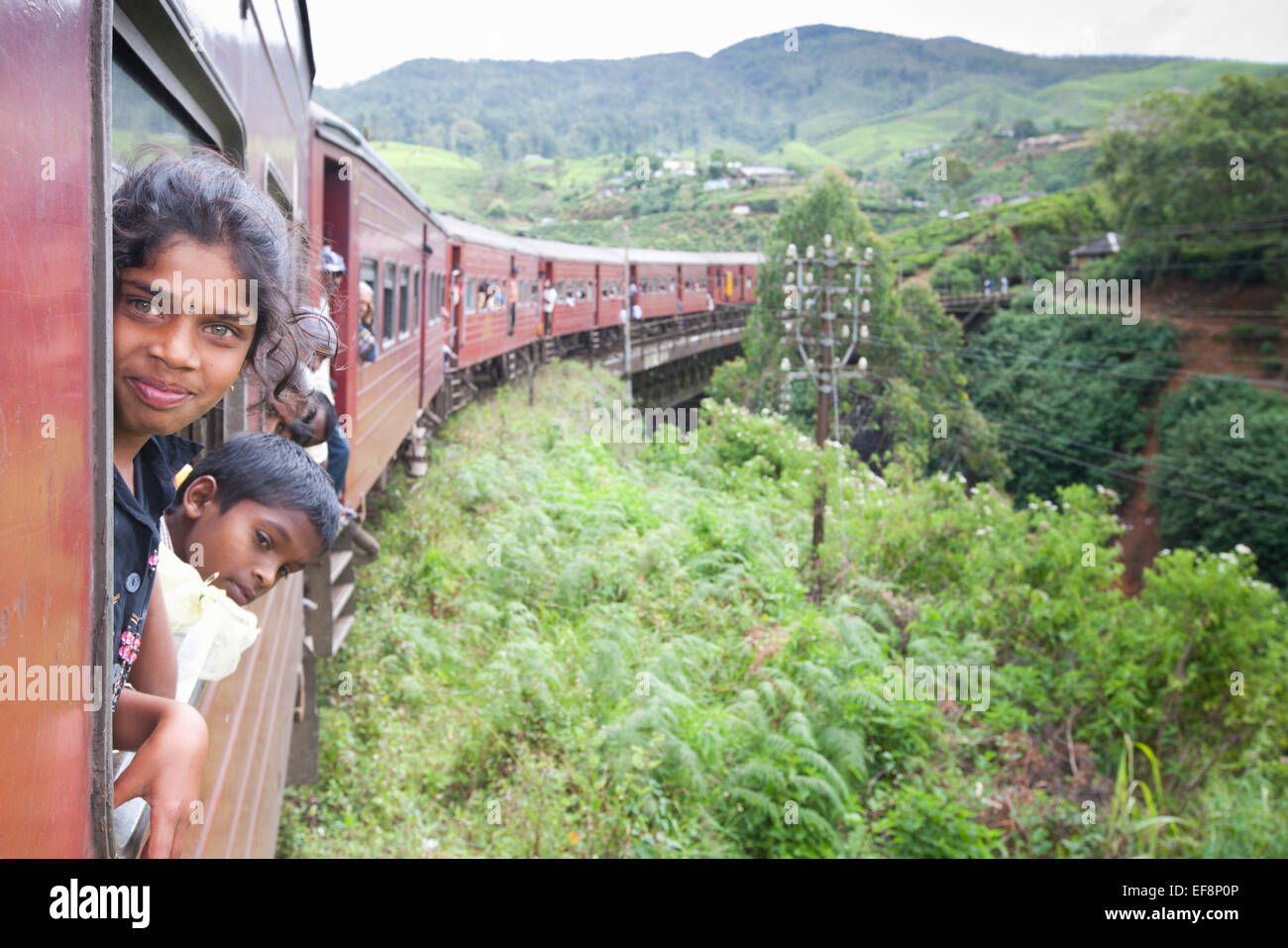 TAMIL GIRL LEANING OUT OF TRAIN WINDOW WHILE TRAVELLING NEAR HAPUTALE Stock Photo
