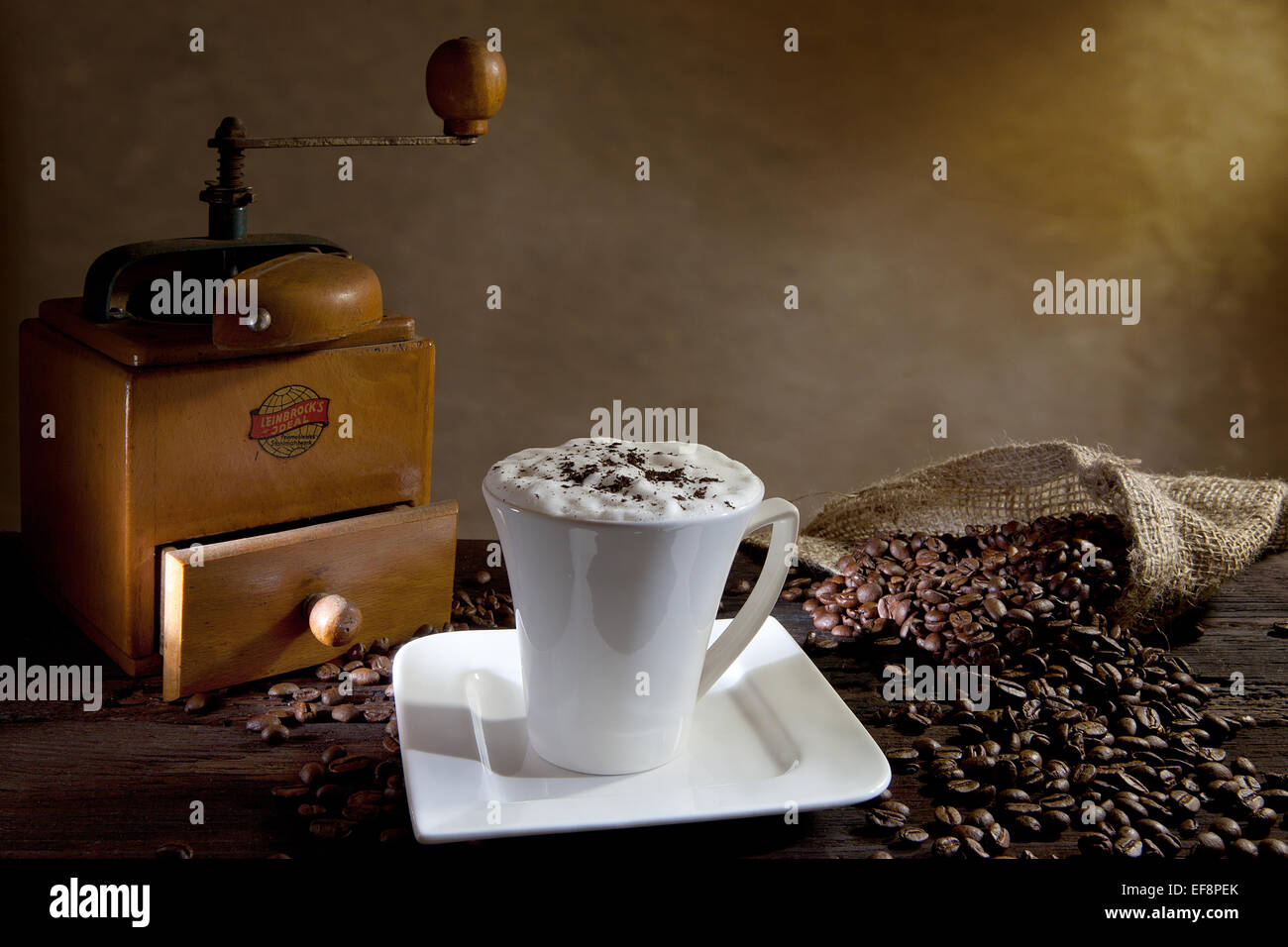 Cup of cappuccino with coffee beans and an old coffee grinder Stock Photo