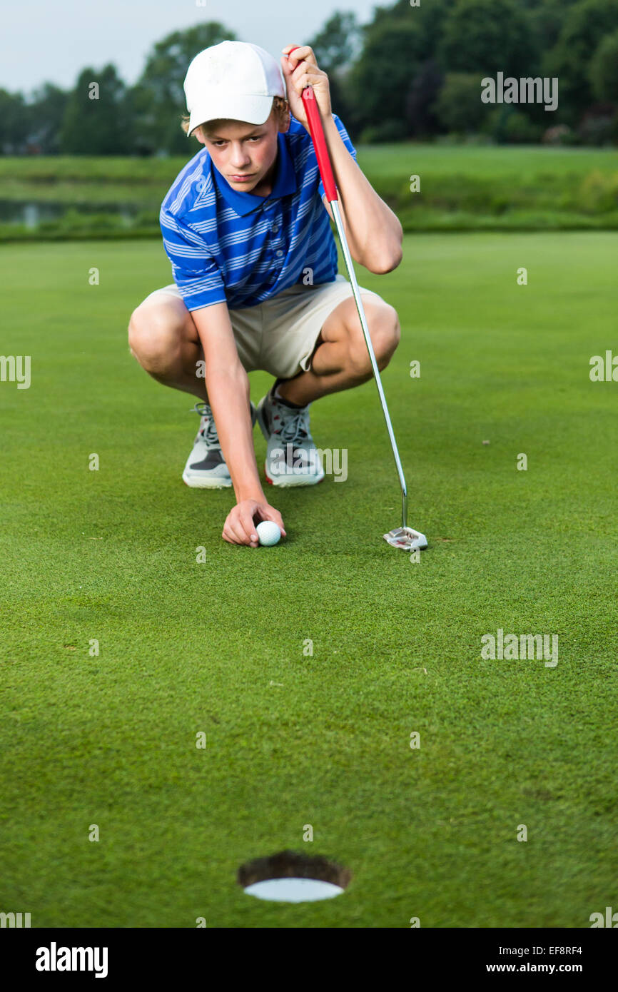 Teenage boy placing ball on tee on golf course Stock Photo Alamy