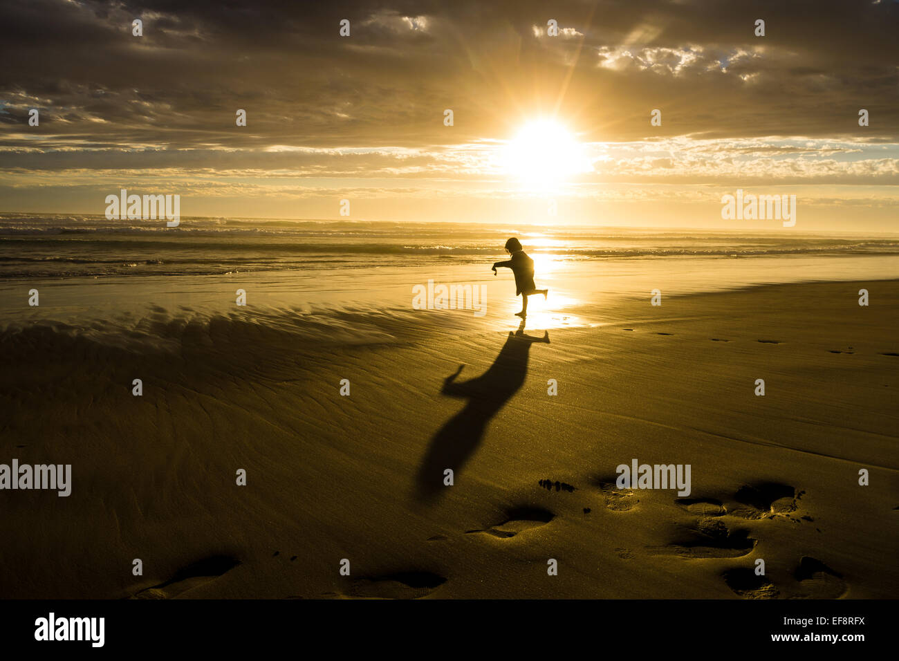 Australia, Melbourne, Silhouette of young girl dancing on beach at sunset Stock Photo