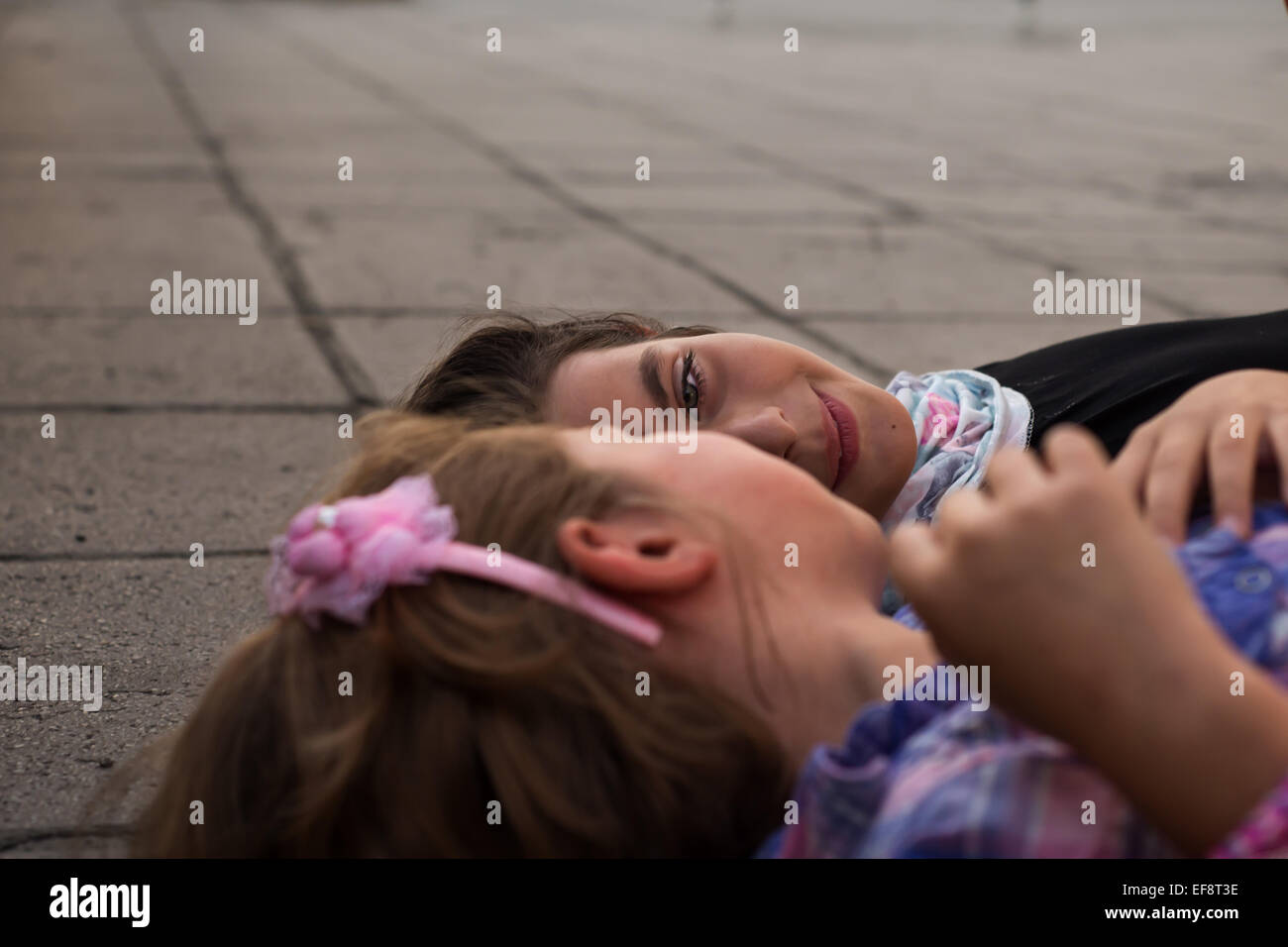 Two girls lying on ground talking Stock Photo