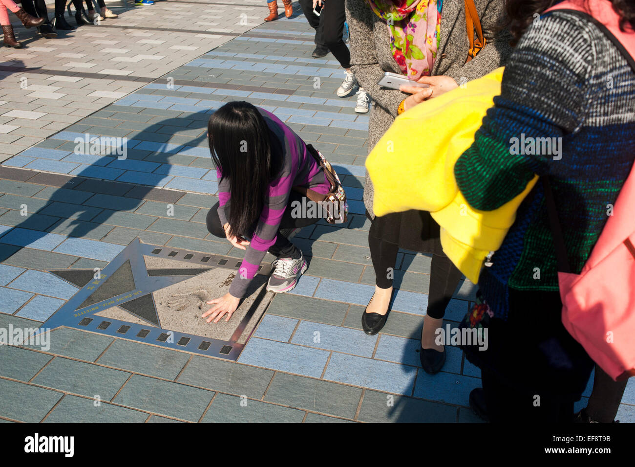 Hong Kong 2015 - Girl places hands to handprints filmstar Jackie Chan on Hong Kong s Avenue of the Stars in Kowloon Stock Photo