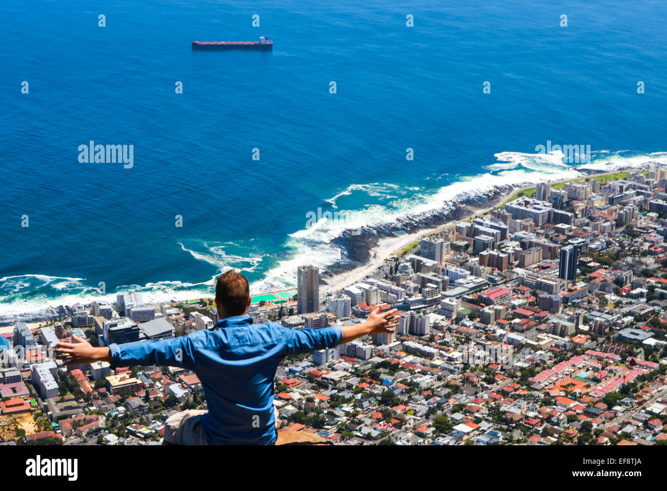 man with arms outstretched, looking at view over cape town from lions head. Stock Photo
