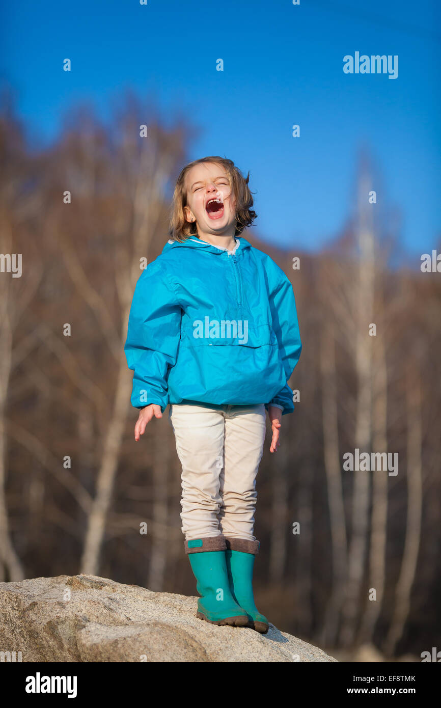 Girl (4-5) standing on rock and shouting Stock Photo