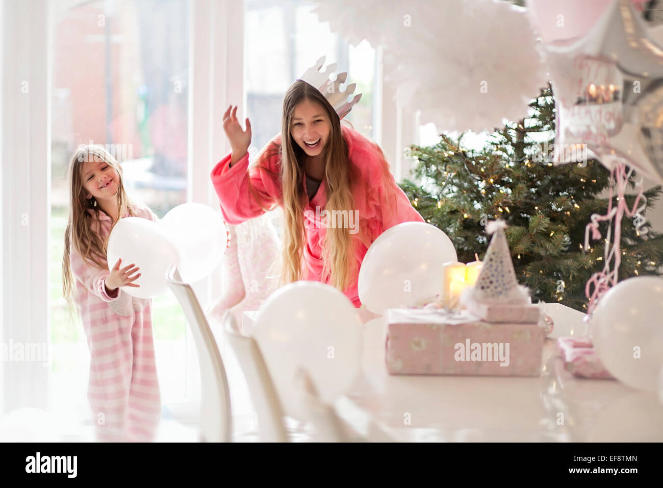 Two girls (4-5,14-15) playing with balloons by Christmas tree Stock Photo