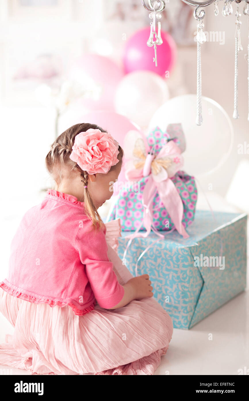 Girl sitting in front of a stack of birthday gifts Stock Photo