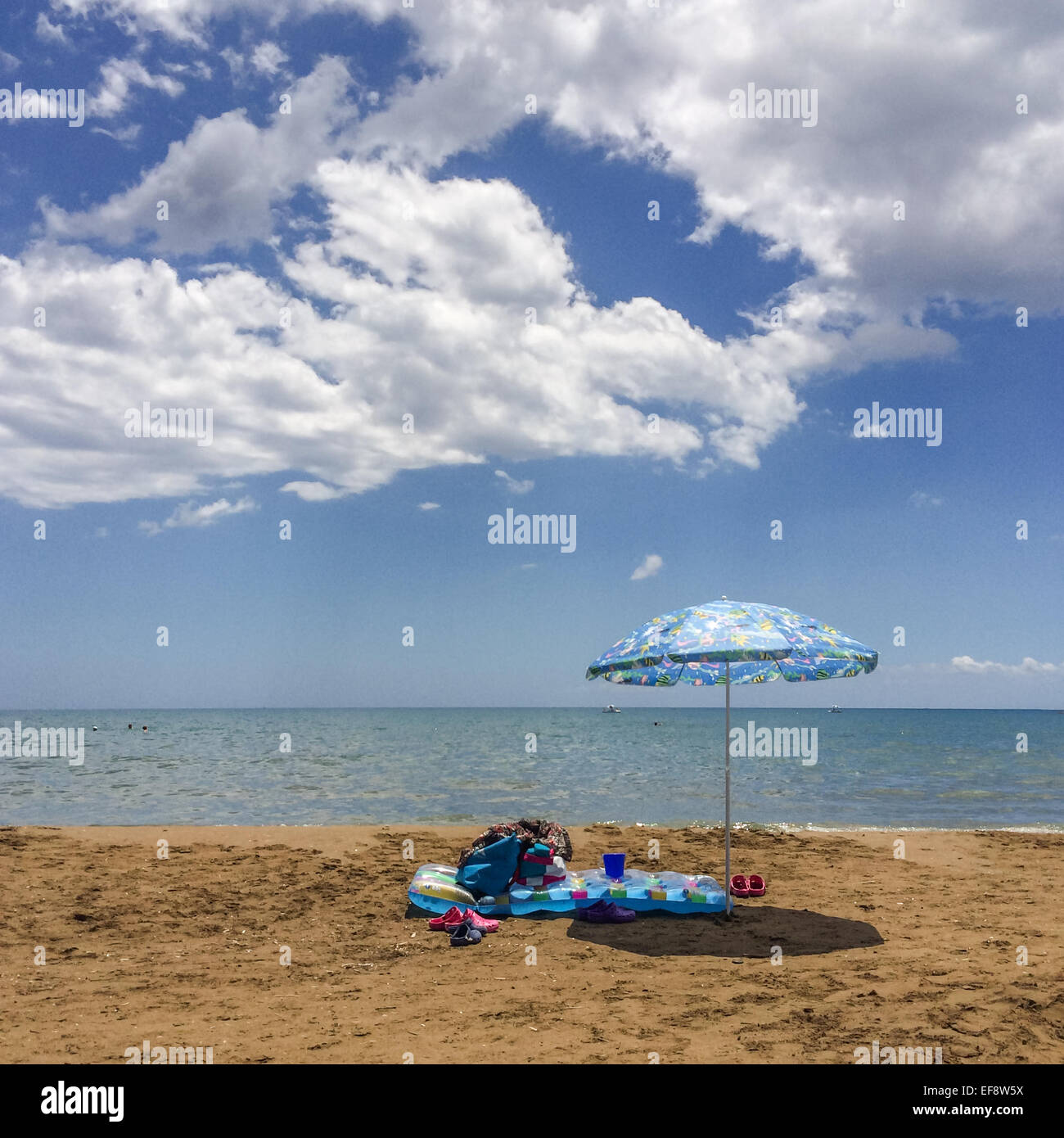 Greece, Zakynthos, Pool raft and umbrella on empty sand beach Stock Photo