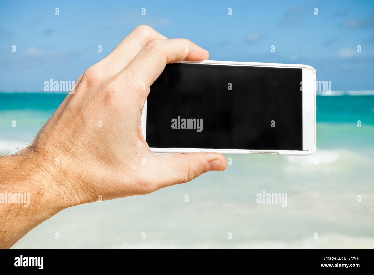 Man using smart phone for taking photo on a beach in Dominican republic Stock Photo