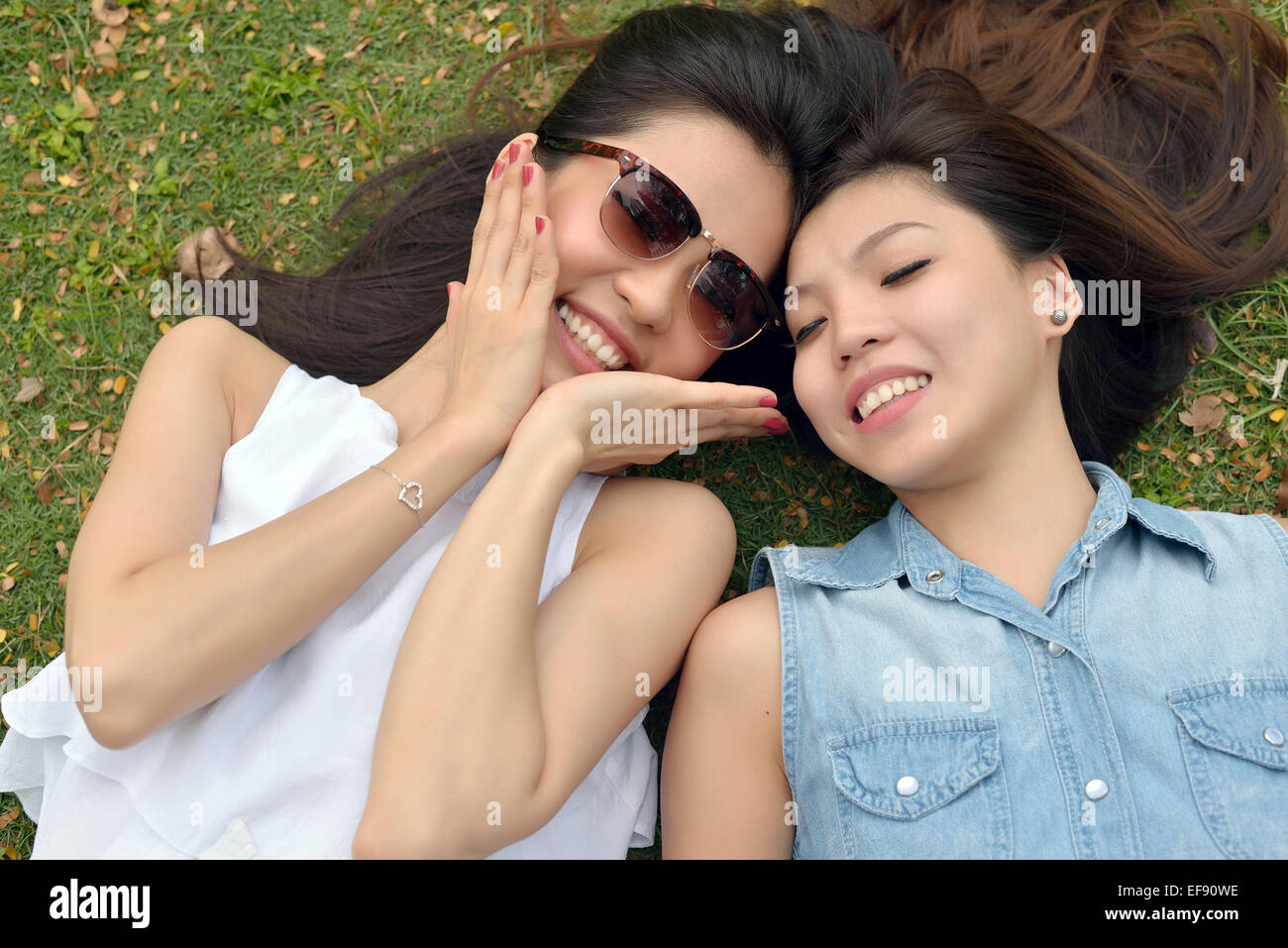 Portrait of Two Beautiful , Young Women , Lie Down on Lawn Stock Photo