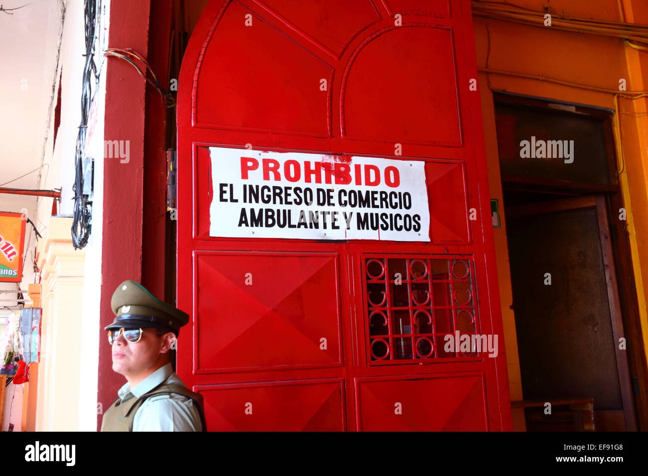 Policeman and sign on entrance to market prohibiting entry of street vendors, informal traders and musicians, Iquique, Chile Stock Photo
